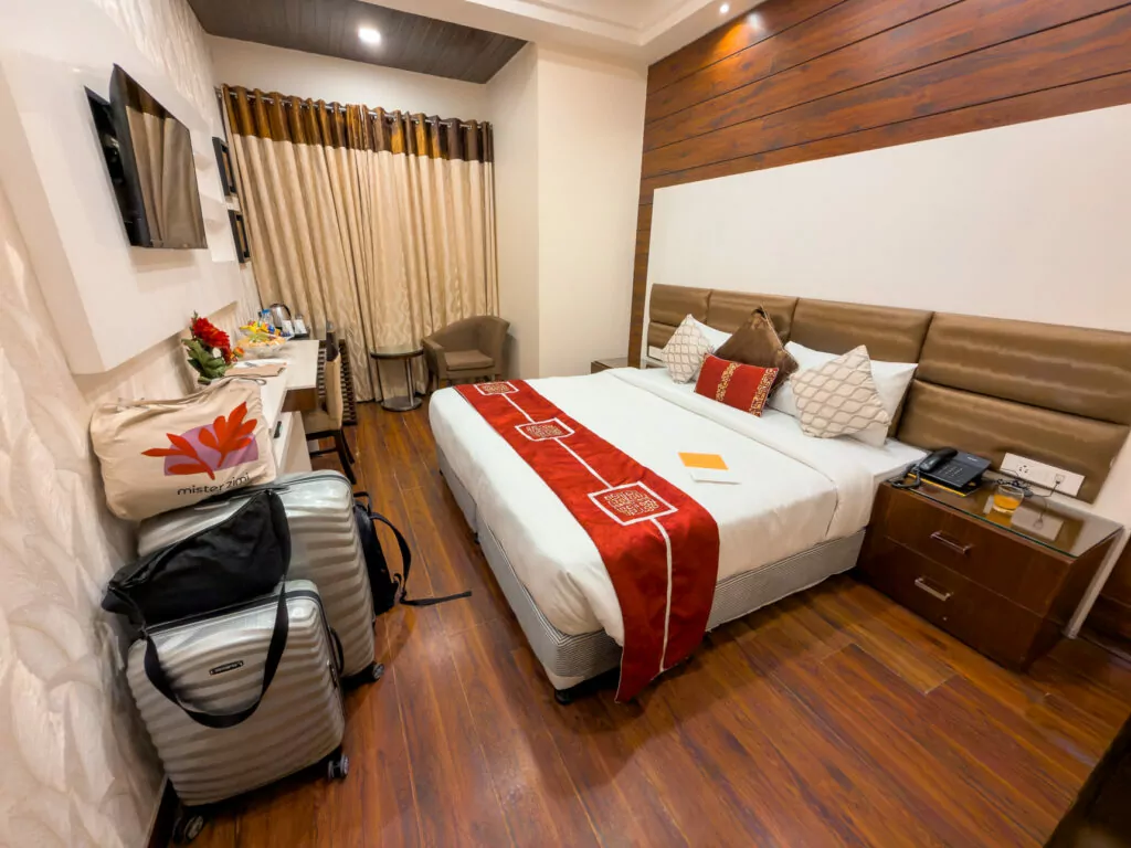 Bedroom at Taj Princess hotel in Delhi with a neatly made bed, wooden accents, and soft lighting