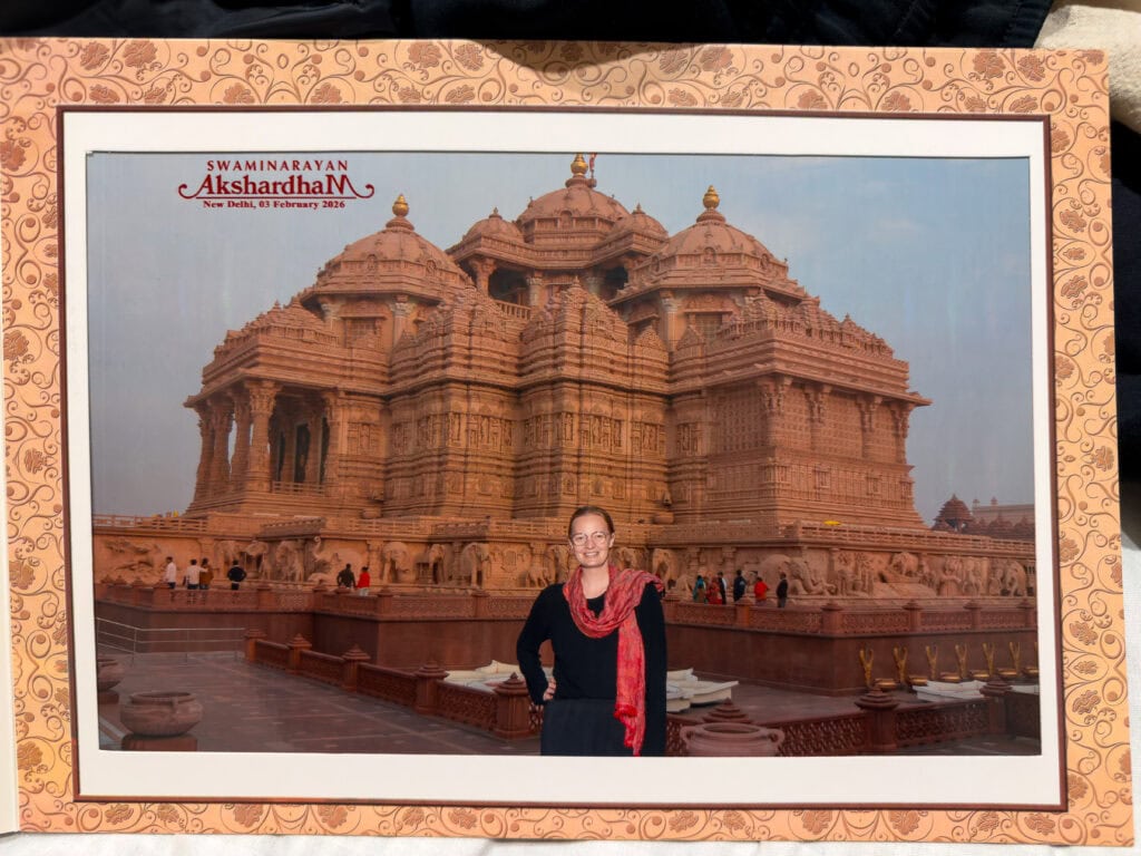 Printed souvenir photo of a traveller posing in front of Akshardham Temple in Delhi, since cameras are not allowed inside. The grand temple architecture is visible in the background