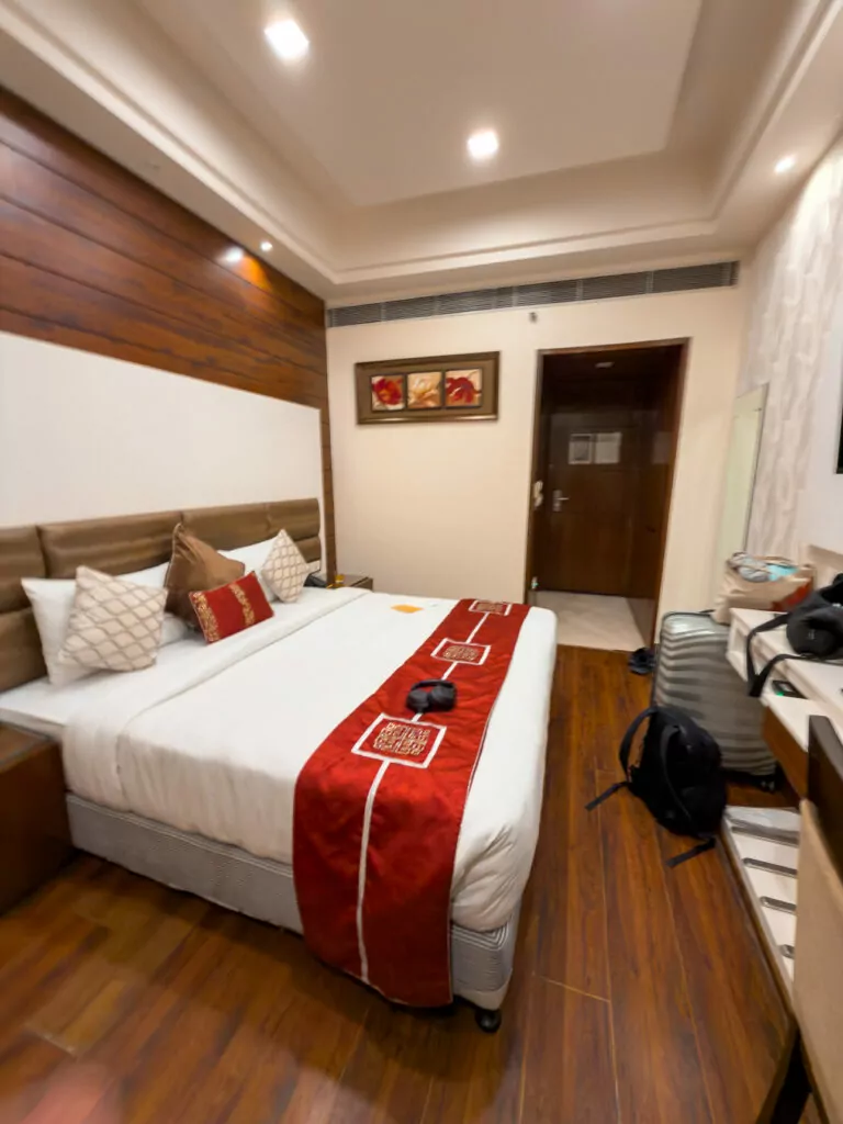 Bedroom at Taj Princess hotel in Delhi with a neatly made bed, wooden accents, and soft lighting