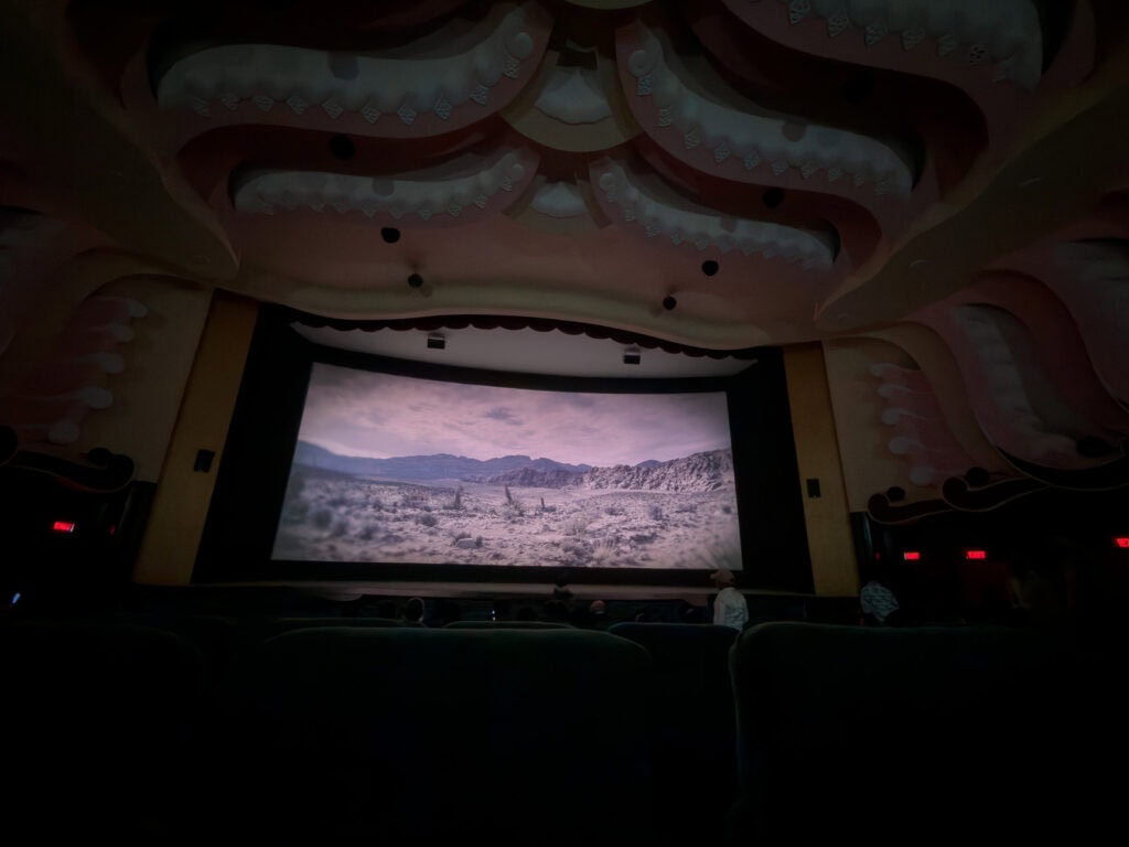 Interior of Raj Mandir Cinema with curved ceilings and a large screen at the front showing a film. The theatre’s distinctive design and soft lighting create a classic Bollywood cinema experience.