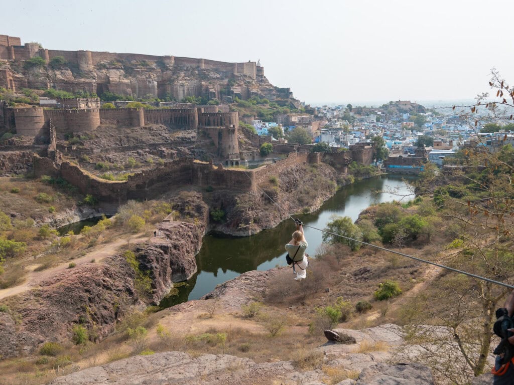 A traveller rides a zipline past Mehrangarh Fort with sweeping views over Jodhpur and the surrounding landscape. This adventurous moment adds variety to an India tour for solo travellers