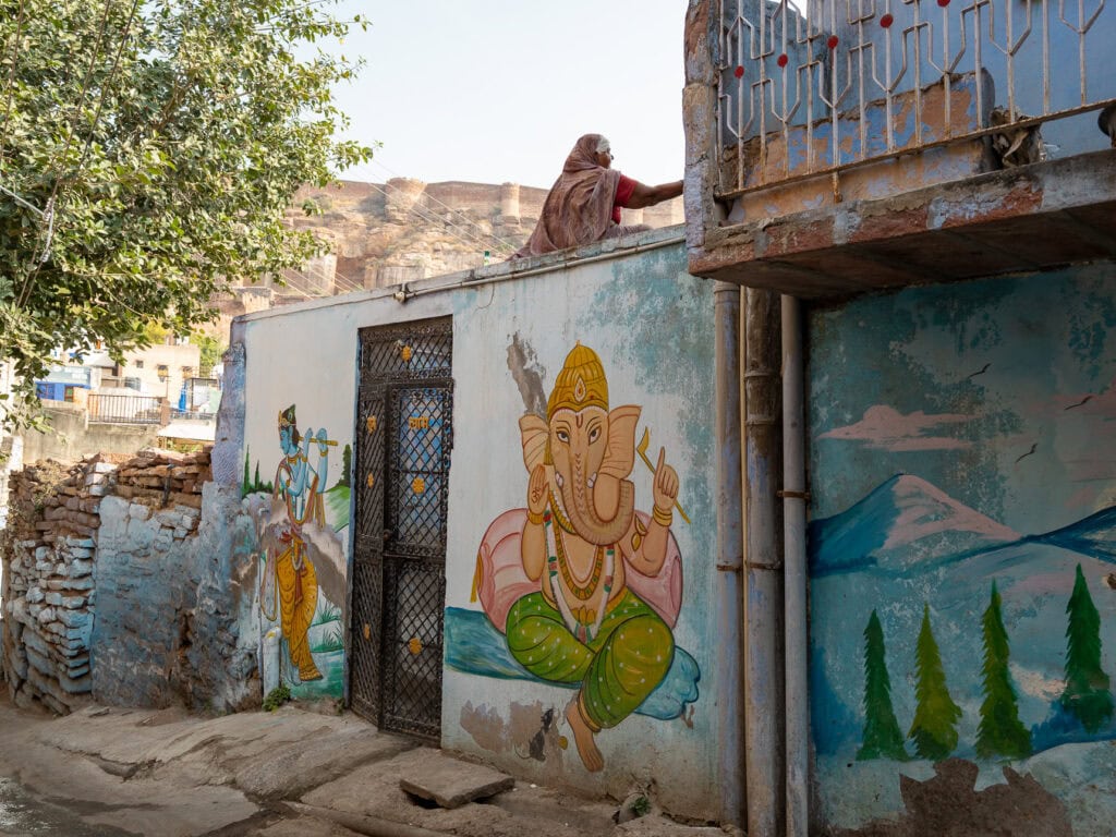 Street in Jodhpur with colourful wall art and painted buildings along a narrow lane. The quiet scene contrasts with the busier parts of the city