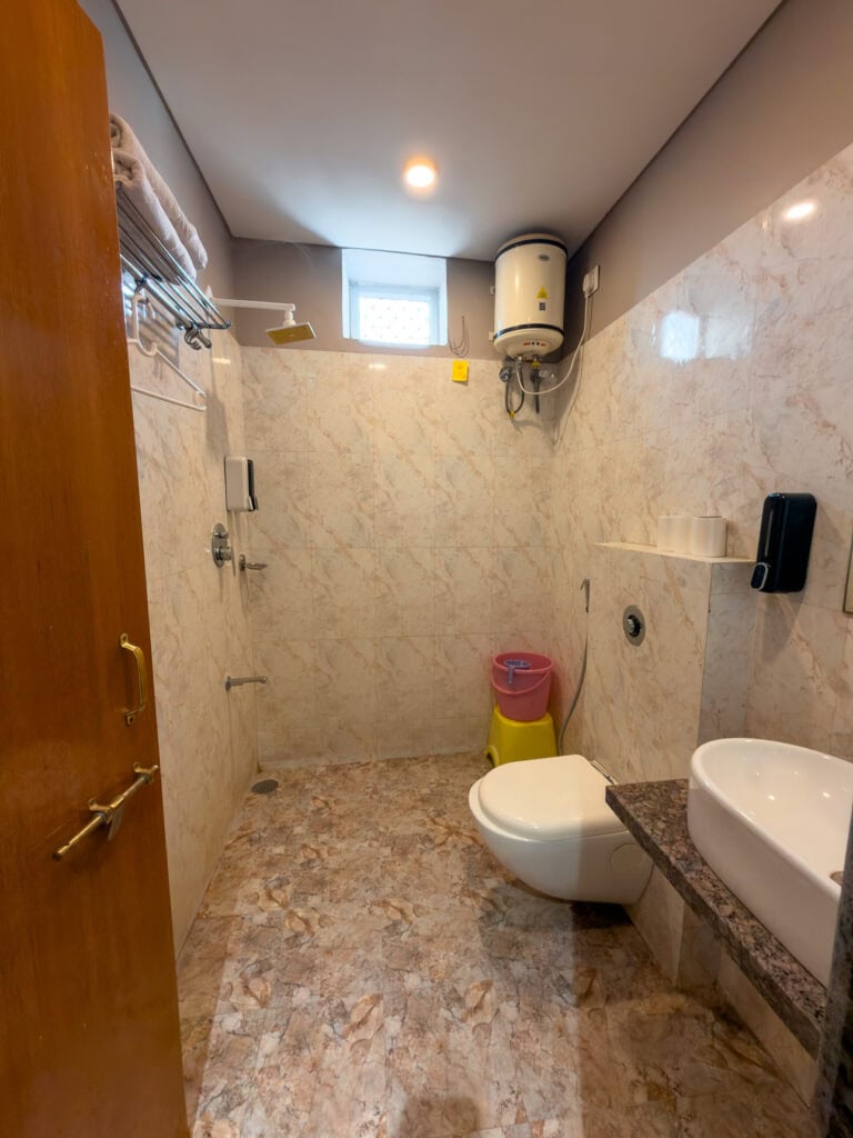 Simple bathroom inside Kuchaman Haveli hotel with tiled walls, a shower, and basic amenities. The space reflects traditional accommodation on an India tour with One Life Adventures