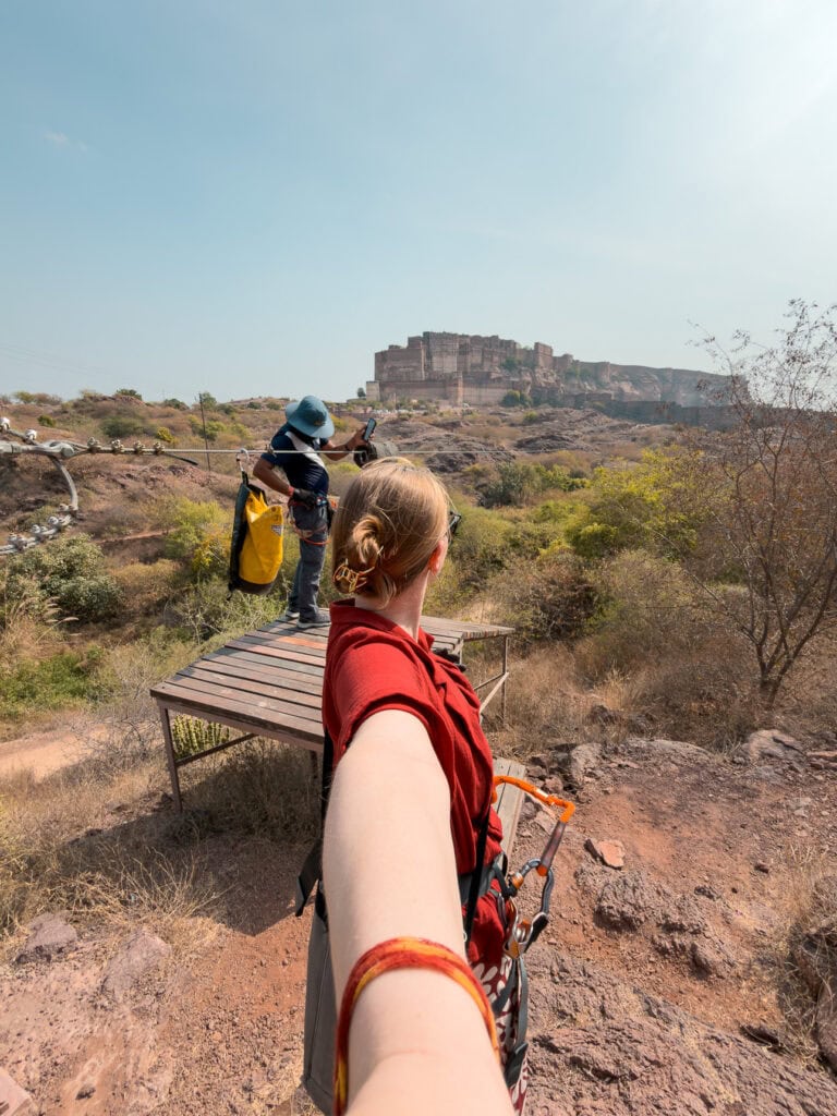 A traveller waiting for their turn on the zipline near Mehrangarh Fort with views over Jodhpur and rocky landscape.