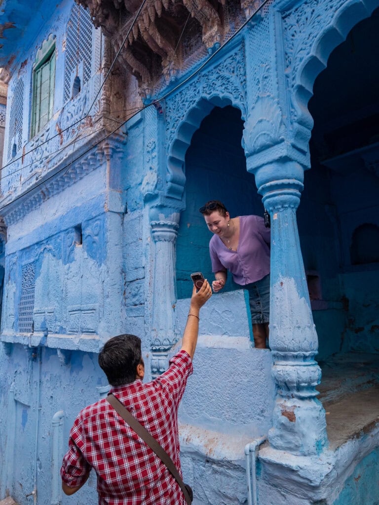 A tour guide takes a photo of a traveller in Jodhpur's Blue City and she smiles at the result, another benefit of booking a One Life Adventures tour in India.