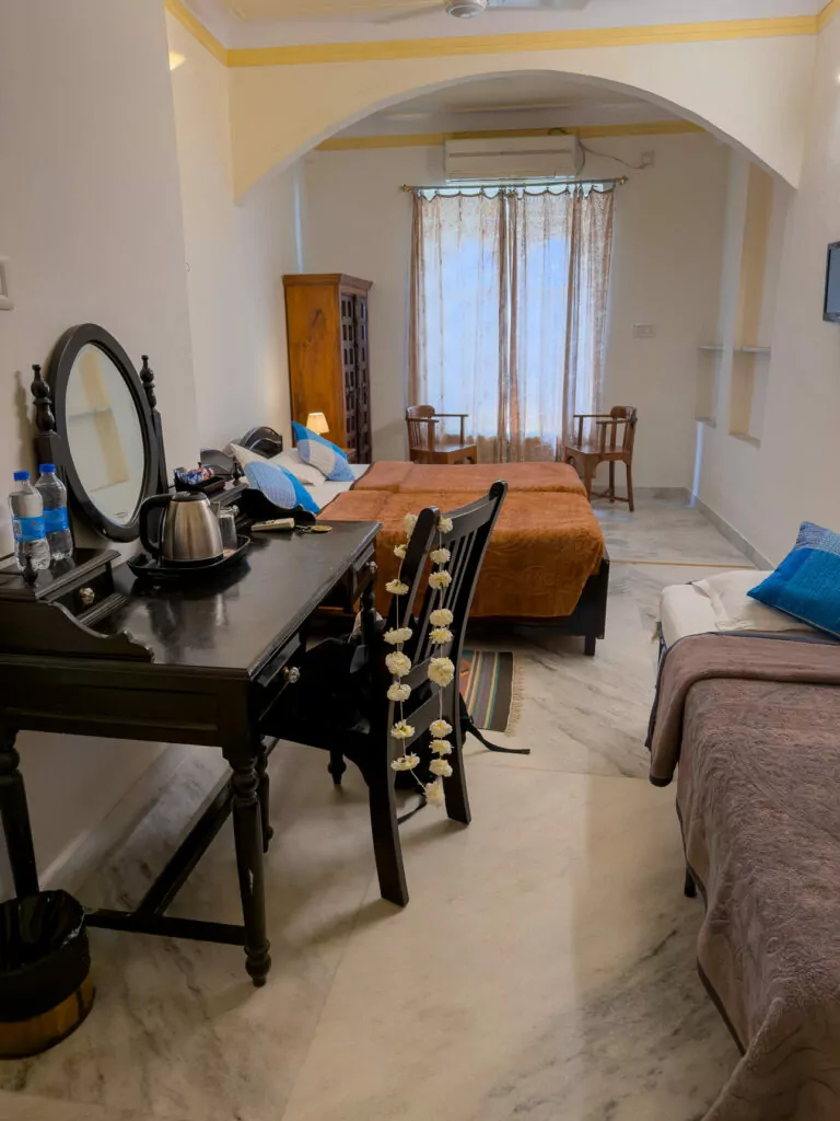 A bedroom at Pratap Bhawan hotel in Udaipur with a neatly made bed, soft lighting, and traditional decor. The space offers a comfortable place to stay during an India tour