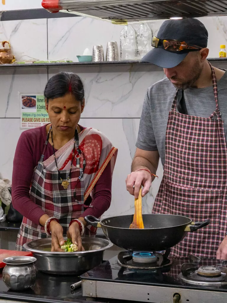 A woman prepares ingredients during a cooking class in Udaipur, standing at a kitchen counter with spices and vegetables. This hands on experience is part of the One Life Adventures India itinerary