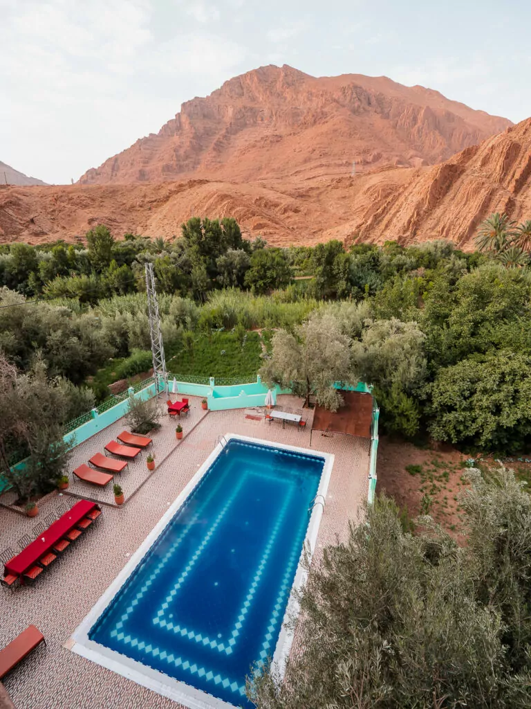 Swimming pool with dramatic red rock cliffs in the background at accommodation in Todra Gorge, Morocco