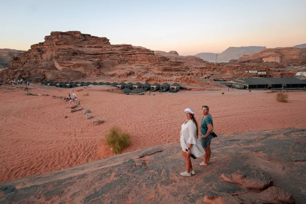 Travellers walking across the red desert sand in Wadi Rum, Jordan, with dramatic rock formations behind them