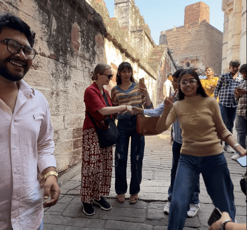 Alexx laughing and interacting with locals as they gather around to take photos together on a street