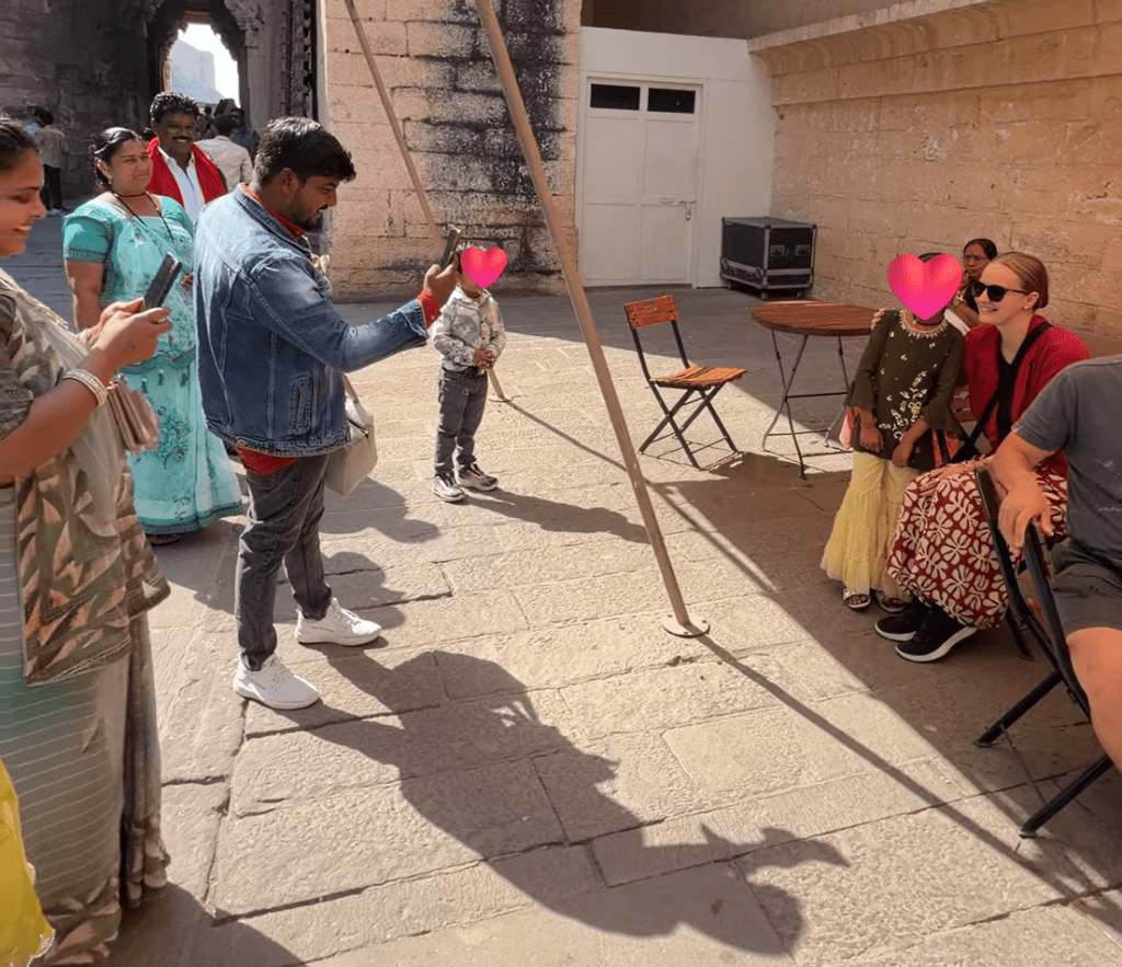 Alexx taking photos with local families and their children who gathered around her in a courtyard