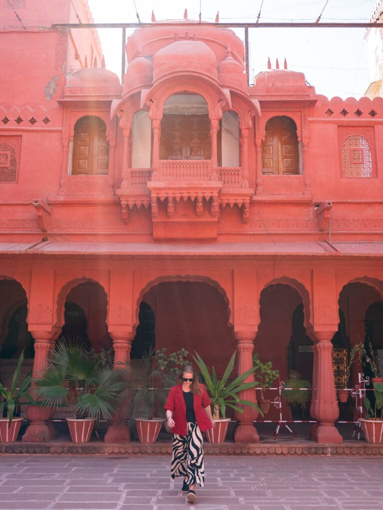Red sandstone building in Bikaner with arched doorways and potted plants lining the courtyard