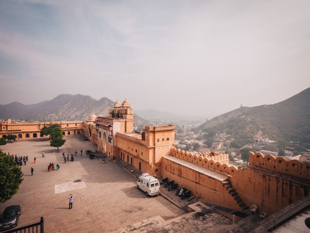 Jaipur fort viewed from above with large sandstone walls, courtyards, and hills fading into the distance