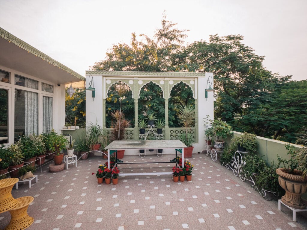 Peaceful courtyard at Ikaki Niwas in Jaipur with an ornamental arch, tiled floor, and plants arranged around a central seating area