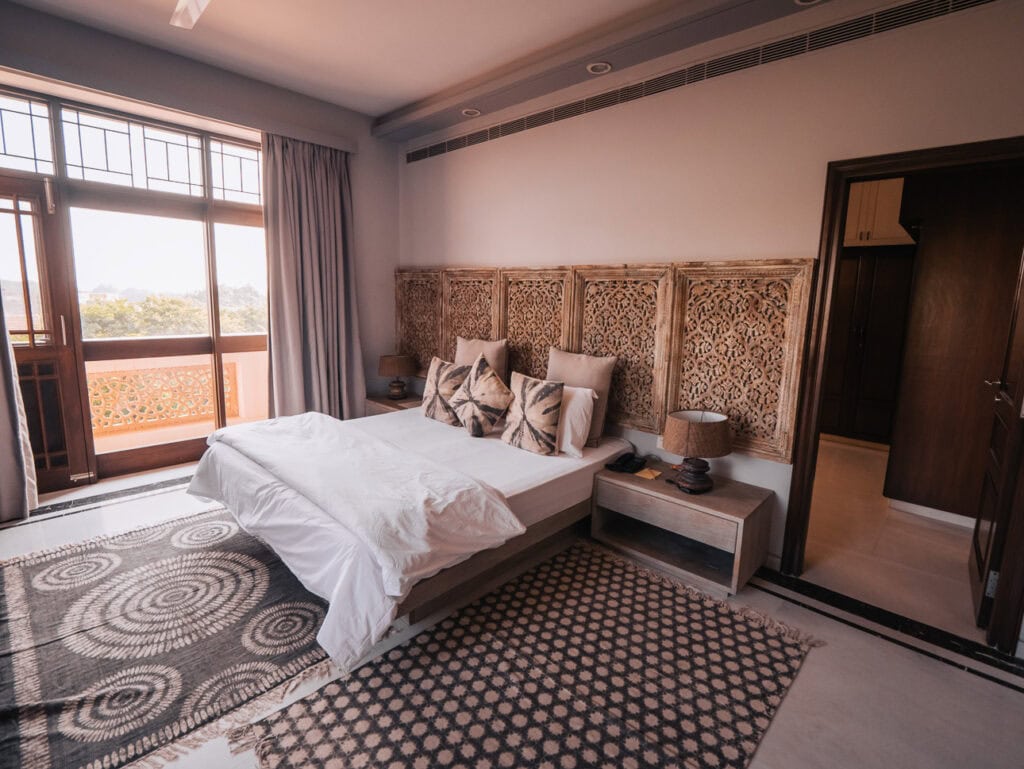 Cozy hotel room with a neatly made bed, patterned cushions, and warm lighting, showing a comfortable place to stay