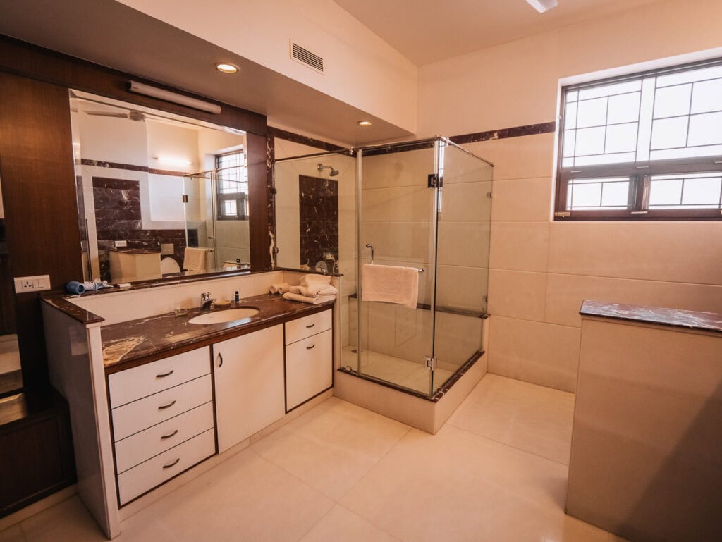 Spacious bathroom with a glass shower, large mirror, and modern fixtures, highlighting clean and practical amenities