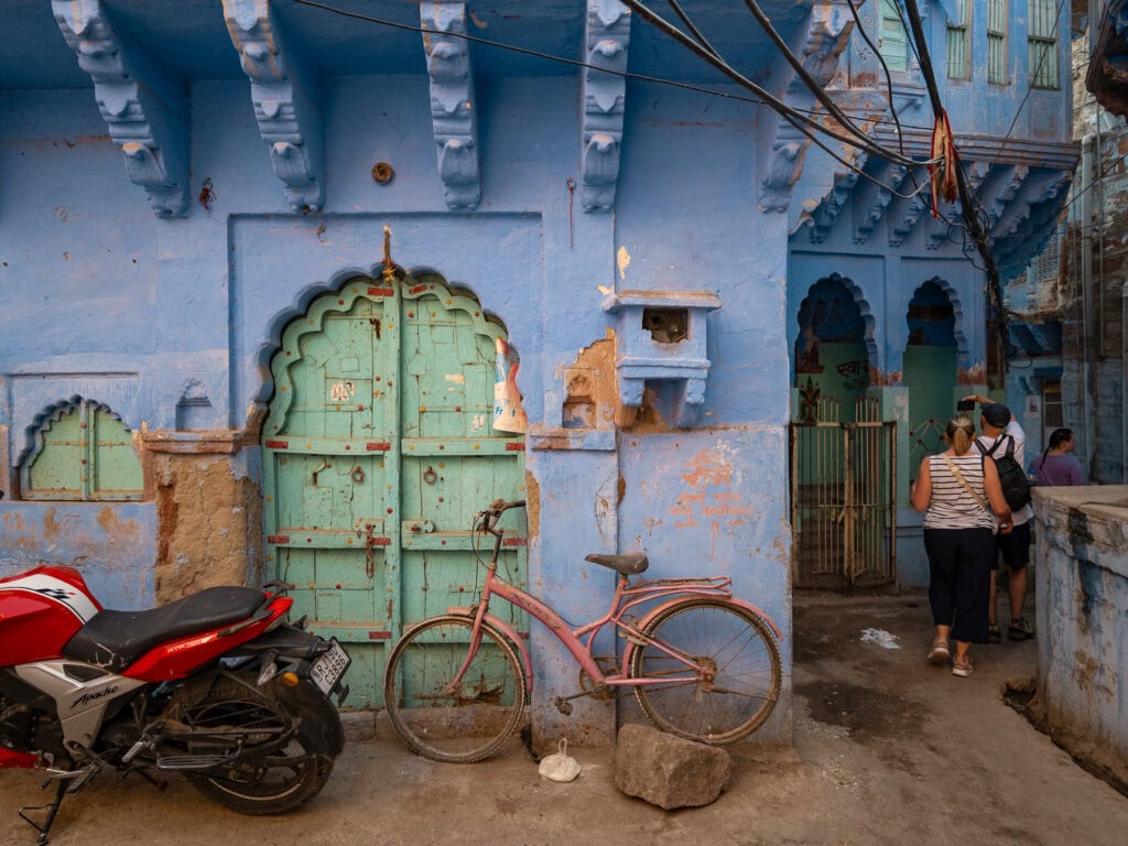 Blue painted building with an arched doorway and a bicycle parked outside, reflecting everyday street scenes in Jodhpur, India