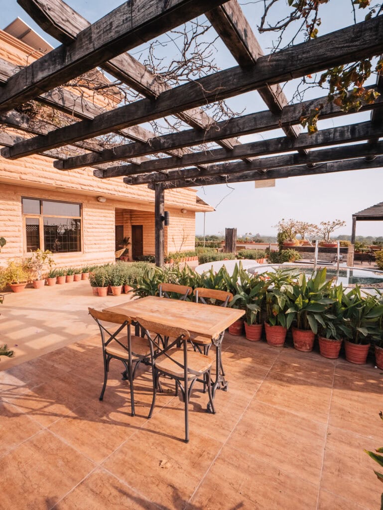 Outdoor terrace with wooden table seating, potted plants, and a pergola overlooking the landscape, offering a peaceful place to relax while traveling