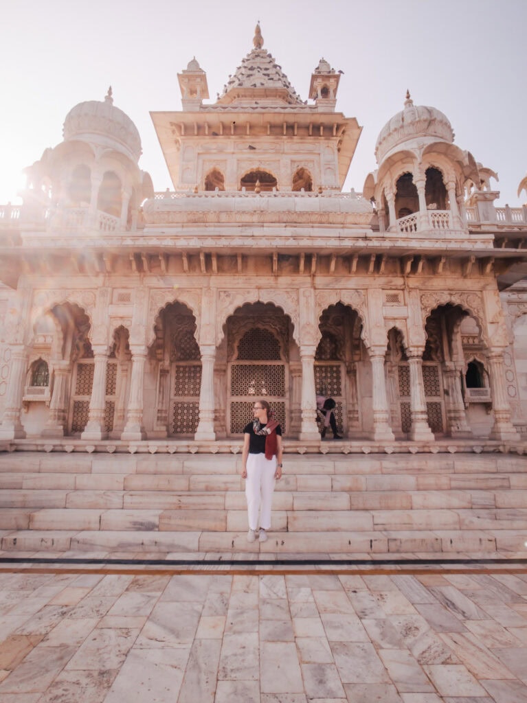 Traveller standing on the steps of a white marble courtyard with arches and domes rising behind her in Jodhpur