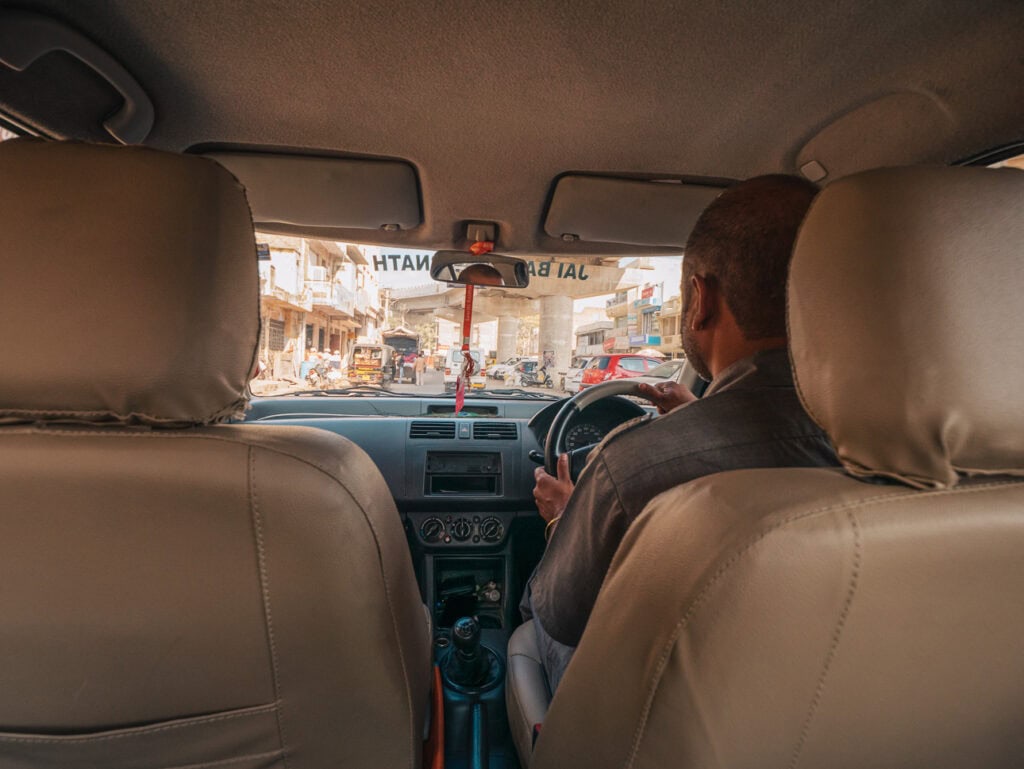 View from the backseat of a car with a private driver in India looking out onto a busy street ahead