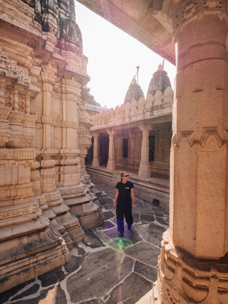 Intricate white marble pillars and domed ceilings inside Ranakpur Jain Temple with a female traveller standing among the carvings