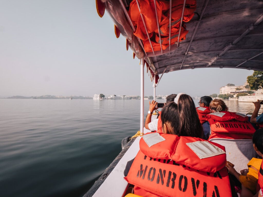 Boat ride on Lake Pichola in Udaipur with passengers wearing life jackets and looking out over the water