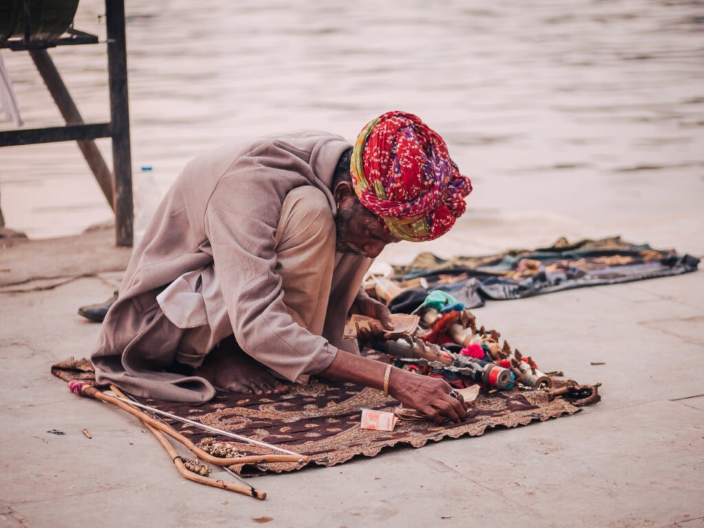 Local vendor sitting on the ground in Udaipur arranging handmade jewellery and textiles by the lakeside