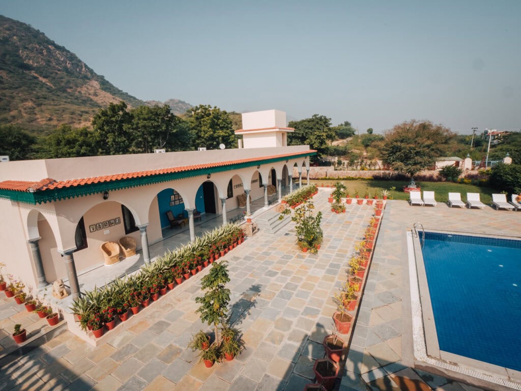 Courtyard at Premkunj Udaipur with a swimming pool, arched walkways, and rows of potted plants, a welcoming stay for women travelling India solo