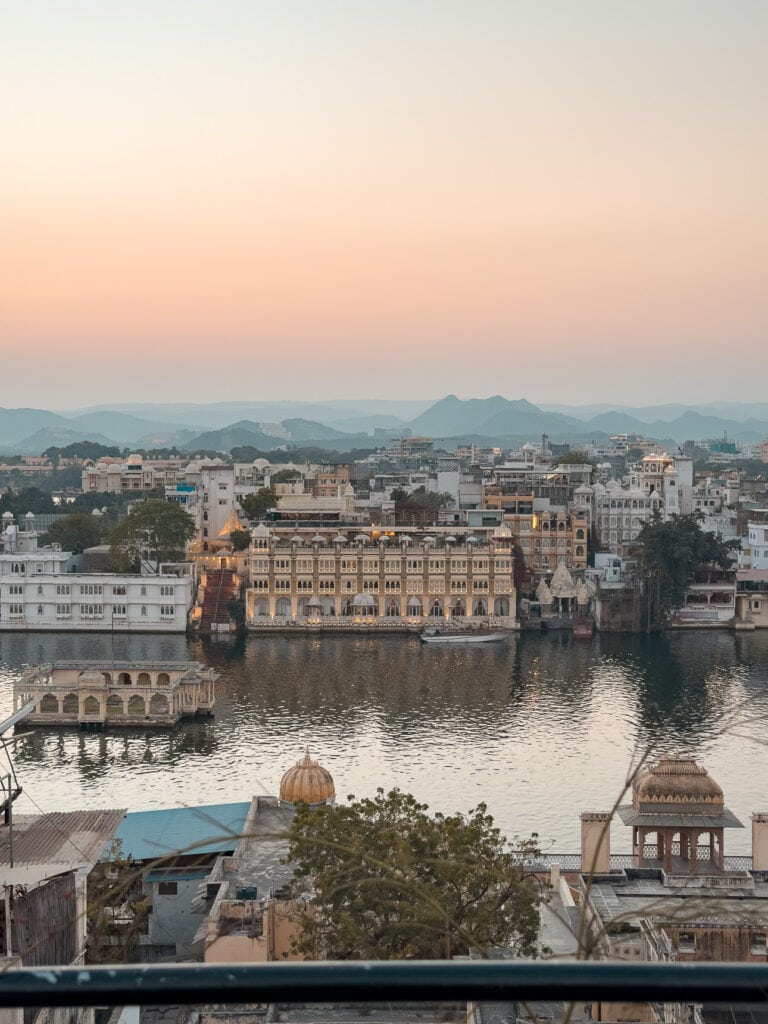 View over Udaipur from a rooftop with Lake Pichola and historic buildings visible in the soft evening light