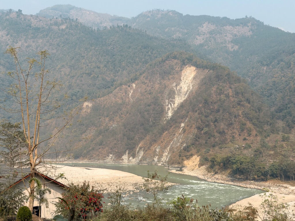 View of the Trishuli River winding through a steep valley with a visible landslide on the hillside