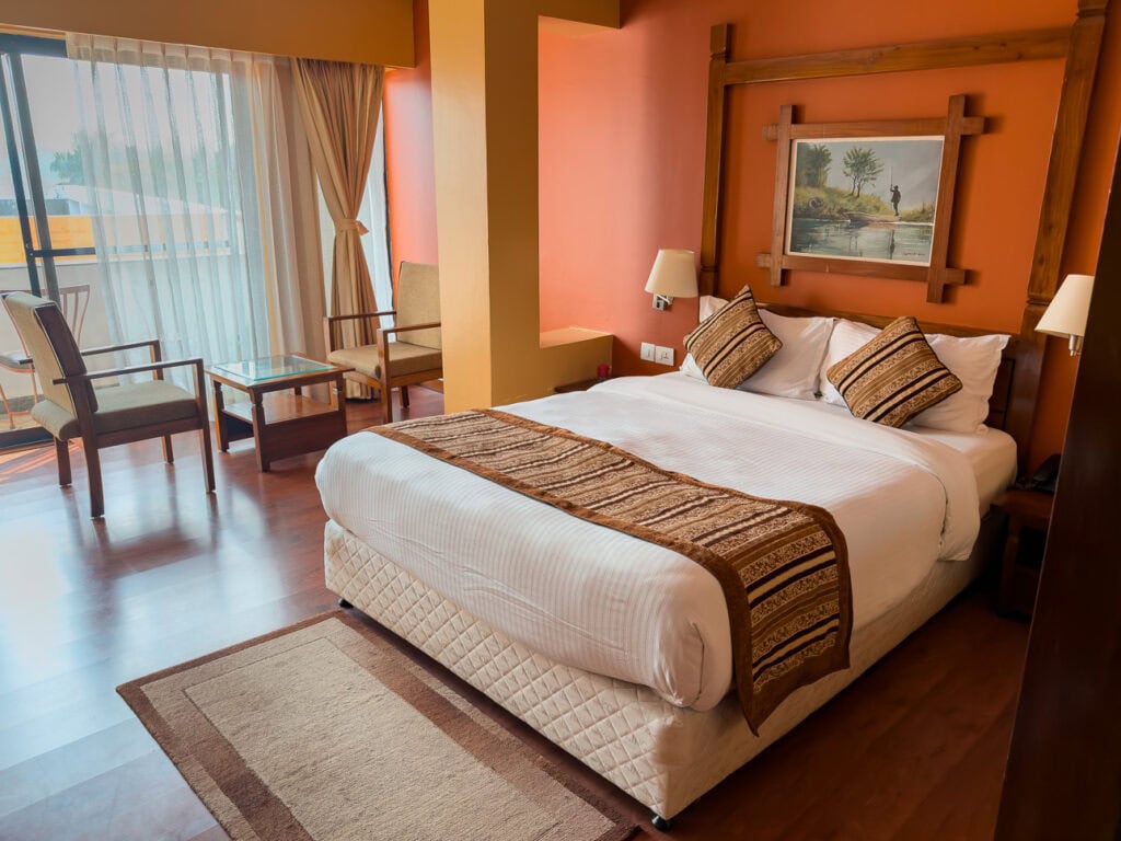 Double bed with cushions in a room at the Landmark Forest Hotel in Chitwan