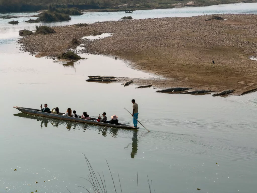 Long wooden canoe on a wide river in Chitwan with people visible in the distance