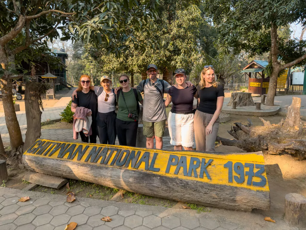 Tour group posing for a photo beside the Chitwan National Park entrance sign on the One Life Adventures Nepal Snapshot tour