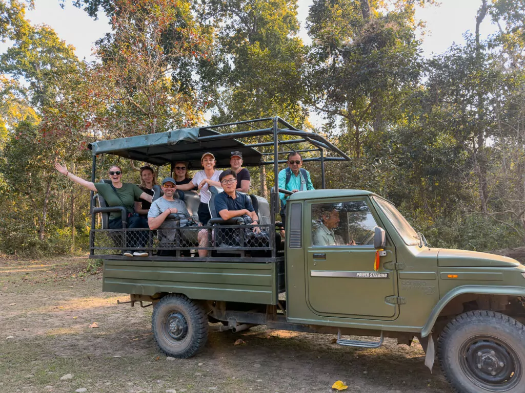 A One Life Adventures tour group taking a group photo in a safari jeep on a jungle trail in Chitwan National Park