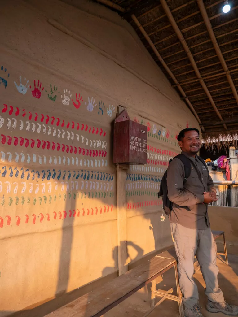 Smiling local tour guide standing in a colourfully decorated room in a village near Chitwan