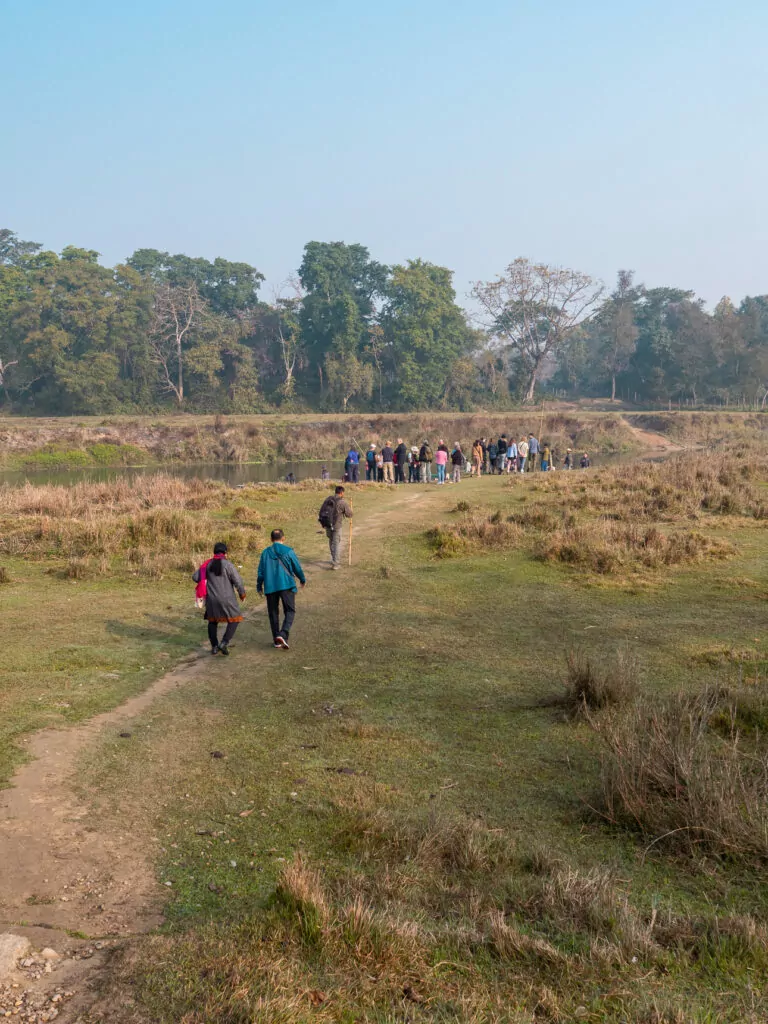 Travellers walking through the grasslands of Chitwan National Park in Nepal