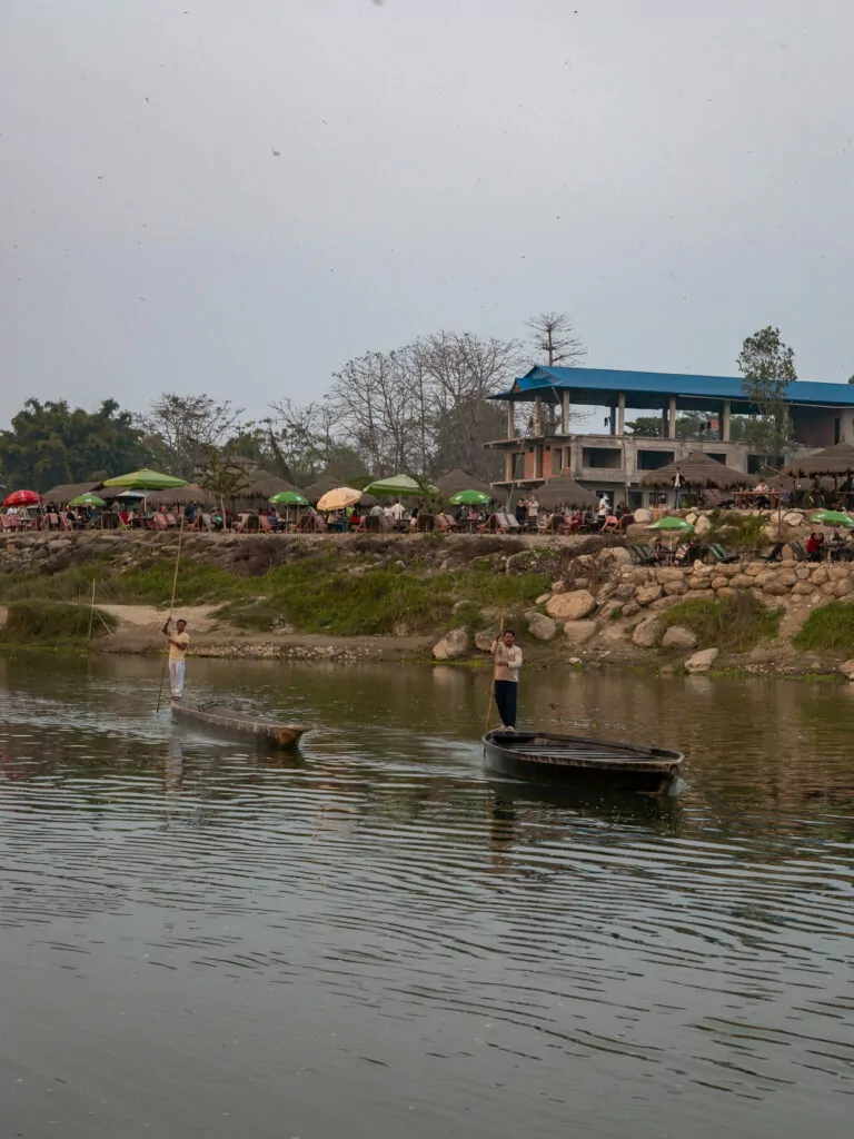 Riverside scenery with trees and umbrellas along the water in Chitwan