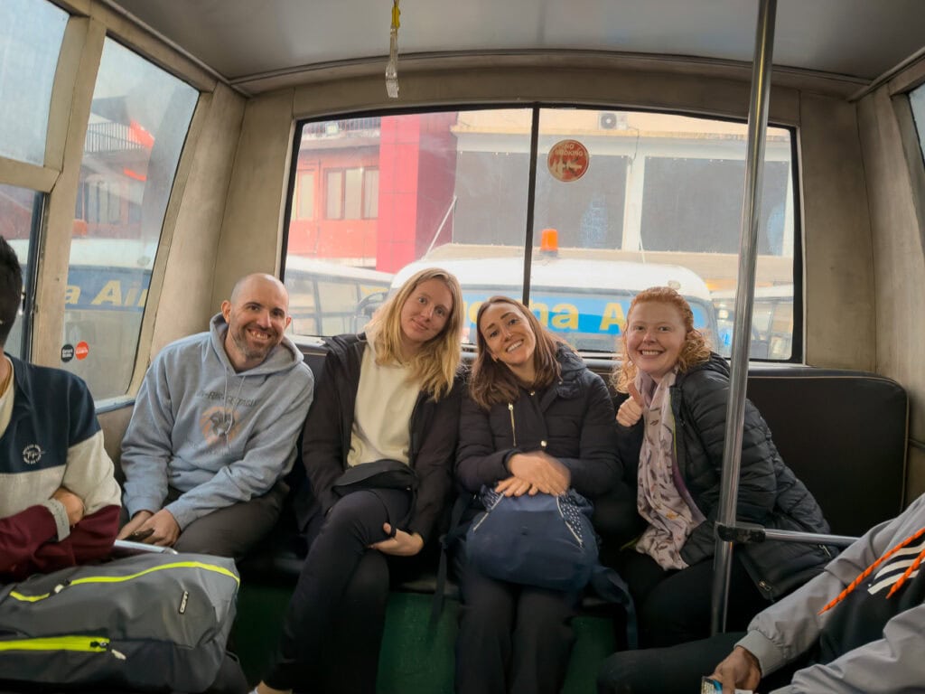 Group of travellers smiling for a photo on the tarmac bus on the One Life Adventures Nepal Snapshot tour