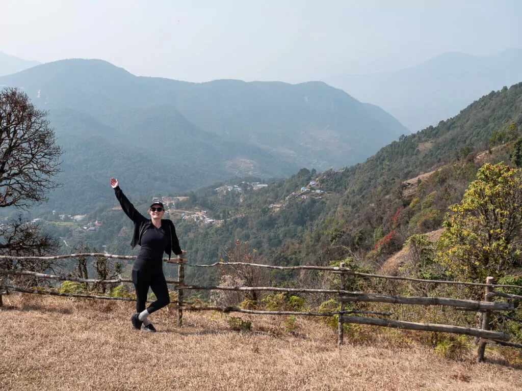 Traveller putting her arms up for a photo at Australian Camp with mountain views behind