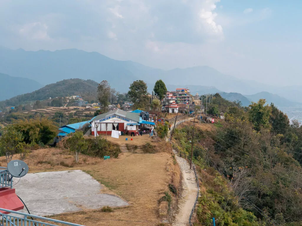 Small hillside village along the Australian Camp trekking route with mountains behind
