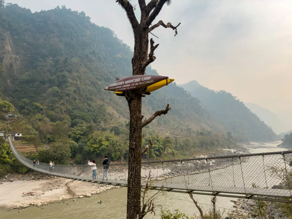 Suspension bridge over the Trishuli River surrounded by forested hills in Nepal