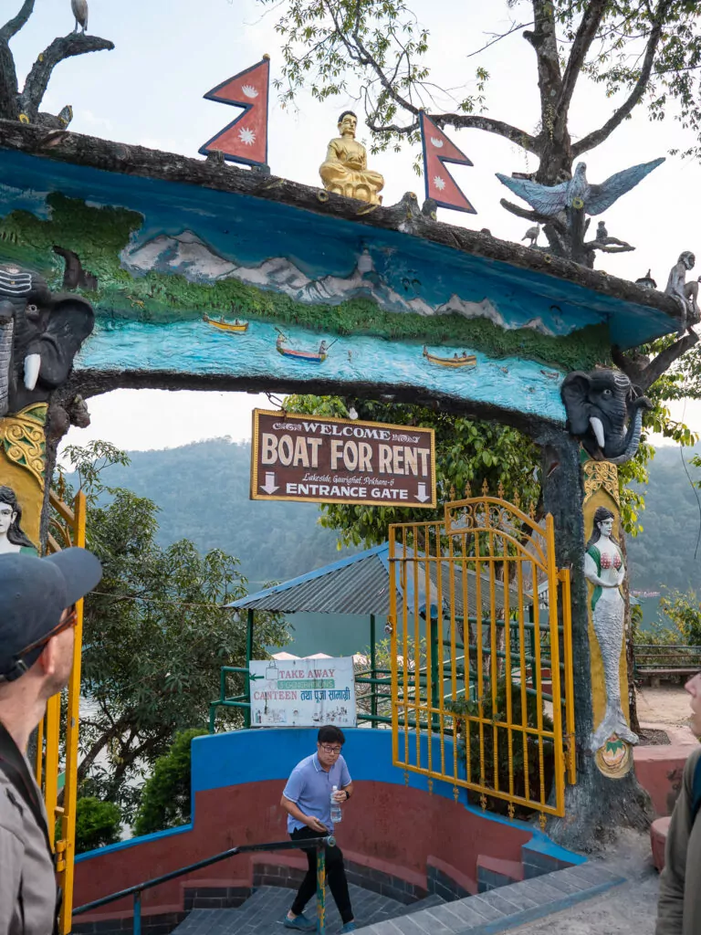 Decorated entrance gate to a boat rental area on Phewa Lake with Nepali flags