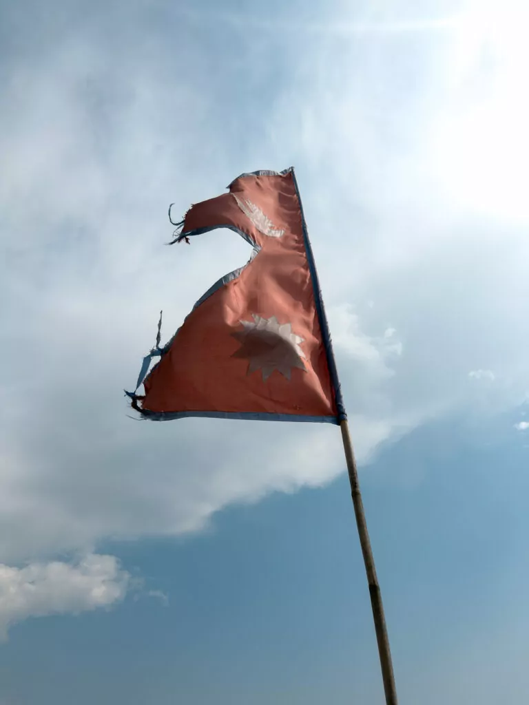 Red flag fluttering against a cloudy sky with mountain reflections on the Australian Camp trek