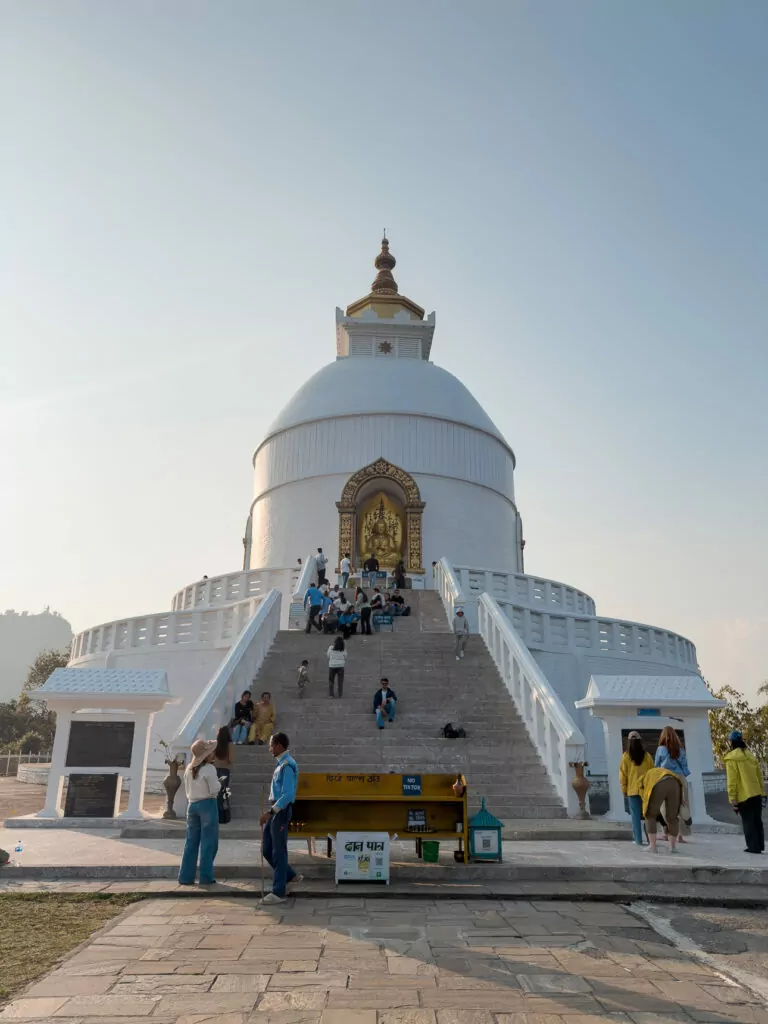 Front view of the World Peace Pagoda in Pokhara with visitors climbing the steps