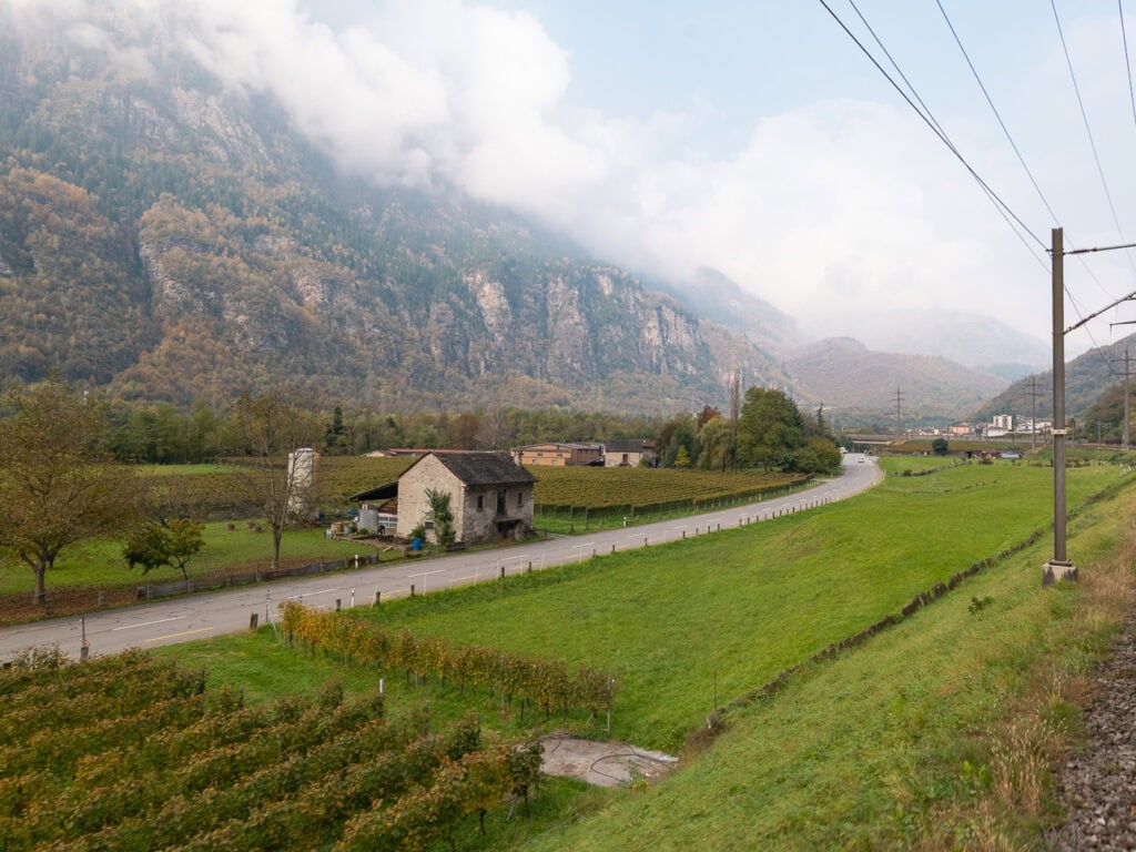 Rows of vineyards stretching toward a Swiss mountain village on the southern end of the Gotthard Railway