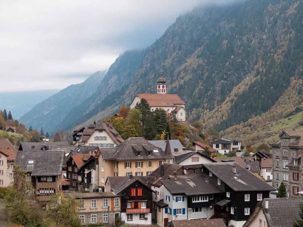 The iconic hilltop Wassen church above a cluster of traditional Swiss chalets along the Gotthard Panoramic Express route
