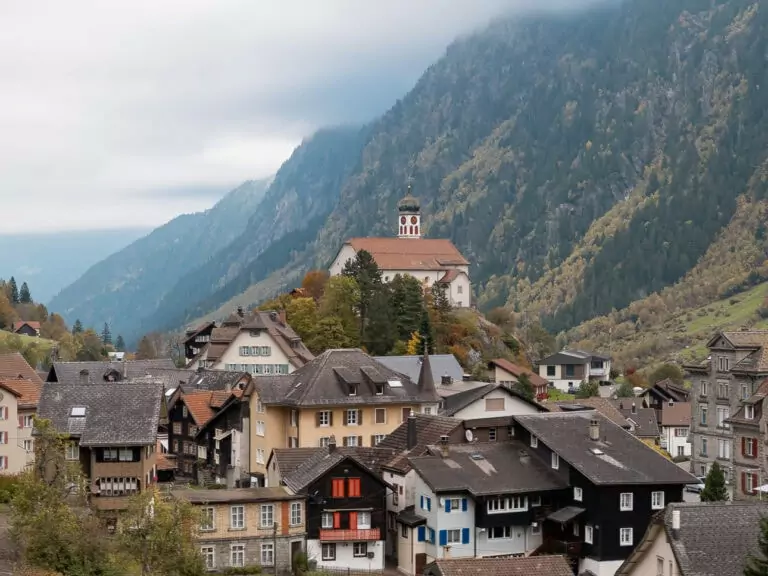 The iconic hilltop Wassen church above a cluster of traditional Swiss chalets along the Gotthard Panoramic Express route