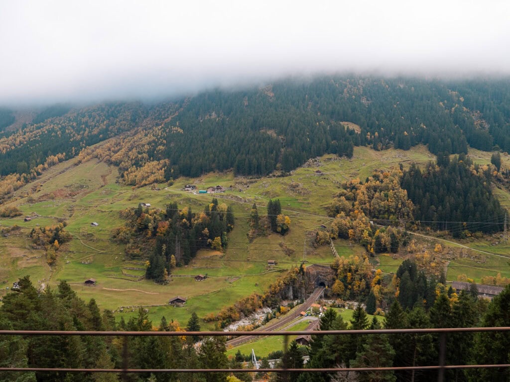 A misty Swiss hillside with autumn trees and scattered farmland