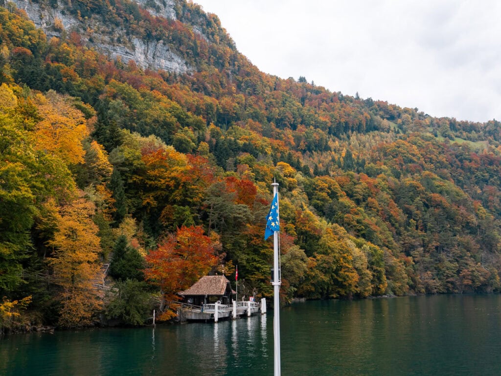 The traditional wooden Rütli boat station on the shore of Lake Lucerne, surrounded by autumn trees