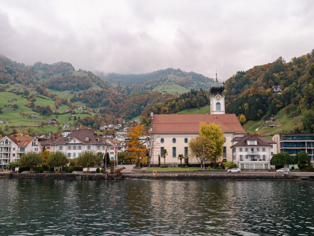 The Flüelen village church reflected in Lake Lucerne on a misty autumn day